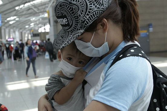 Um modo de tentar se proteger do contágio é a utilização de máscaras de proteção descartáveis. A imagem mostra uma mãe com seu filho no Aeroporto Internacional de Incheon, na Coreia do Sul. (Imagem: Chung Sung-Jun/Getty Images)
