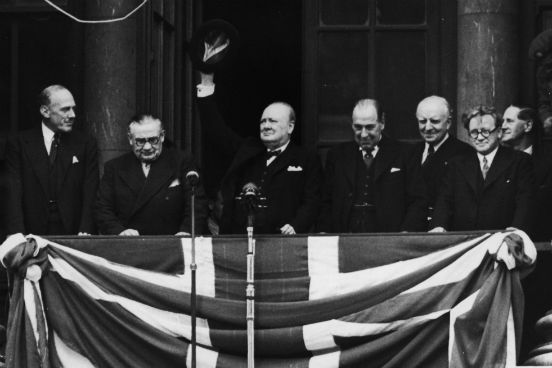 O Primeiro Ministro da Inglaterra Winston Churchill discursa para a multidão reunida ao redor do Ministério da Saúde em Whitehall no dia 8 de maio de 1945. (Créditos: Central Press/Hulton Archive/Getty Images)