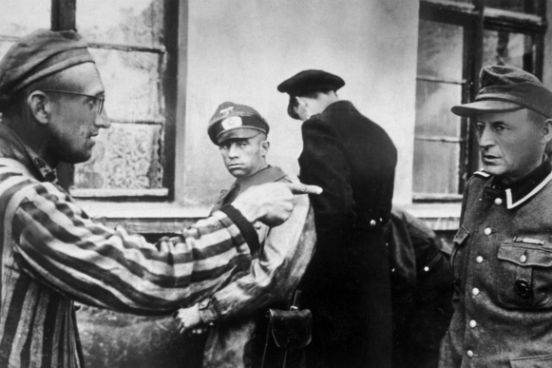 Um trabalhador escravo russo que estava entre os presos libertados pelo exército americano aponta para um guarda nazista que havia espancado brutalmente os prisioneiros. (Créditos: Harold M Roberts/Getty Images)