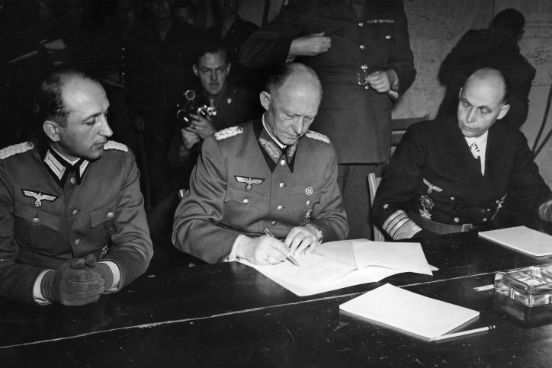 O General Alfred Jodl, conselheiro militar de Hitler e chefe da equipe de operações do Alto Comando Germânico (ao centro) assina o documento de rendição das forças armadas alemãs em Reims, na sede do General Eisenhower. (Foto: Keystone / Getty Images)