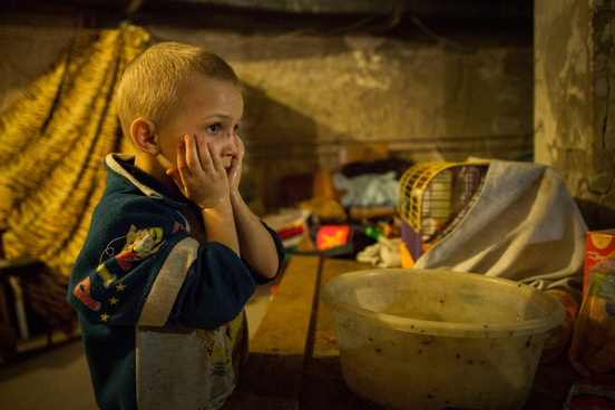 As crianças Pavel Makeev, de cinco anos de idade, e Raya Makeeva, de sete, esperam o almoço ficar pronto no porão de um centro cultural no leste da Ucrânia, onde vivem atualmente. A região tem sido fortemente atacada por forças ucranianas, obrigando a maioria dos moradores a fugir ou a se esconder em lugares como esse. As pessoas têm vivido no espaço desde junho de 2014. (Foto: Andrew Burton / Getty Images)