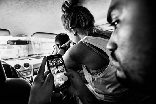 Líder do coletivo independente de mídia Papo Reto recebe uma imagem pelo celular que mostra um taxista morto pela polícia. O Papo Reto foi criado por um grupo de jovens do Morro do Alemão para divulgar reportagens de sua comunidade (Crédito foto: Sebastián Liste/Noor). Líder do coletivo independente de mídia Papo Reto recebe uma imagem pelo celular que mostra um taxista morto pela polícia. O Papo Reto foi criado por um grupo de jovens do Morro do Alemão para divulgar reportagens de sua comunidade (Crédito foto: Sebastián Liste/Noor).
