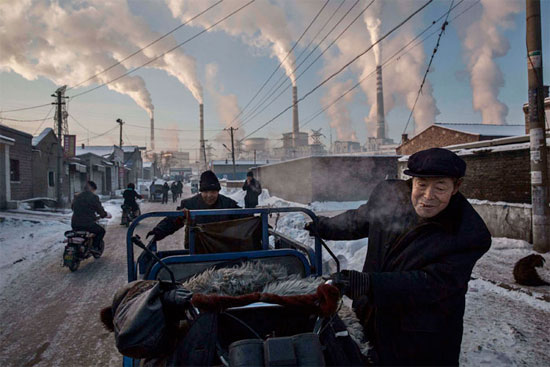 Homens carregam um triciclo em região próxima à usina de carvão em Shanxi, na China. O país é responsável por quase um terço de todo o dióxido de carbono emitido no planeta. O uso do carvão para a geração de energia é uma das principais causas do aquecimento global (Crédito foto: Kevin Frayer/Getty Images).