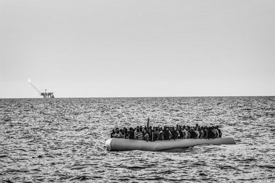 Um bote de borracha conduzindo dezenas de migrantes tenta cruzar o Mar Mediterrâneo para chegar da Líbia até a Itália (Crédito foto: Francesco Zizola/Noor).