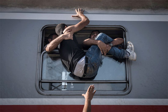 Refugiados tentam embarcar em um trem em Tovarnki, na Hungria, com destino a Zagreb, na Croácia (Crédito foto: Sergey Ponomarev/The New York Times).