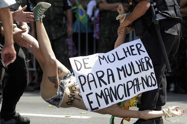 Police officers detain a protester in support of Femen, during a civic-military parade commemorating the Independence Day of Brazil in Brasilia