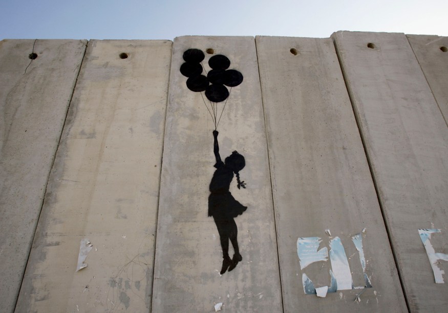 <span>Este grafite é do britânico Banksy, um dos mais renomados artistas contemporâneos, ainda que sua verdadeira identidade seja desconhecida. A imagem é de 2005 e nos mostra a enorme barreira que separa Israel dos territórios palestinos na Cisjordânia, em Ramallah. A silhueta de uma garota segurando balões infláveis é simples em sua crítica à construção do muro e ao mesmo tempo criativa em relação ao desejo de ultrapassar essa barreira imposta pelas autoridades israelenses. </span>(foto: Marco Di Lauro/Getty Images)