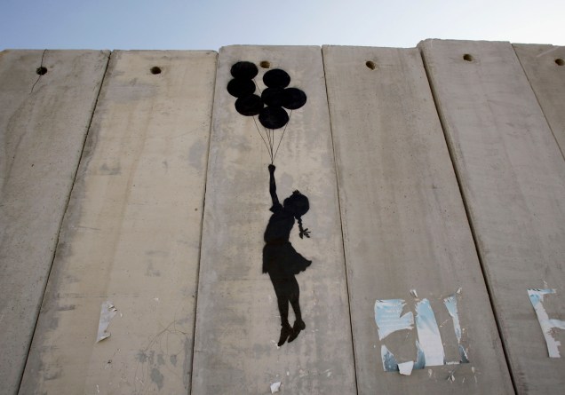 <span>Este grafite é do britânico Banksy, um dos mais renomados artistas contemporâneos, ainda que sua verdadeira identidade seja desconhecida. A imagem é de 2005 e nos mostra a enorme barreira que separa Israel dos territórios palestinos na Cisjordânia, em Ramallah. A silhueta de uma garota segurando balões infláveis é simples em sua crítica à construção do muro e ao mesmo tempo criativa em relação ao desejo de ultrapassar essa barreira imposta pelas autoridades israelenses. </span>(foto: Marco Di Lauro/Getty Images)