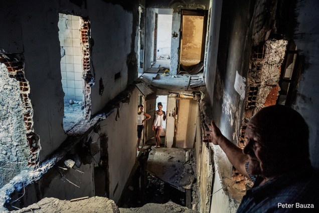 Um pastor mostra o prédio abandonado onde mora, que também é ocupado por outras famílias sem-teto, em julho de 2015.

<span>(foto: Peter Bauza/World Press Photo 2017)</span>