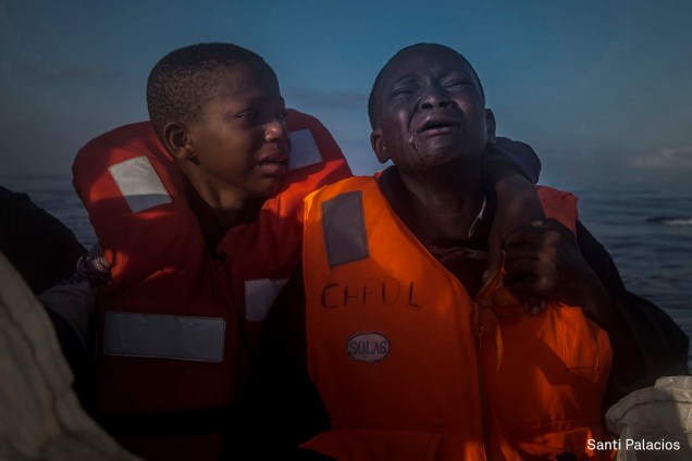 Garota nigeriana chora ao lado de seu irmão após saber que sua mãe morrera na Líbia, em julho de 2016. Eles estão em um barco de resgate após navegar por horas em um bote inflável pelo Mar Mediterrâneo.

<span>(foto: Santi Palacios/World Press Photo 2017)</span>