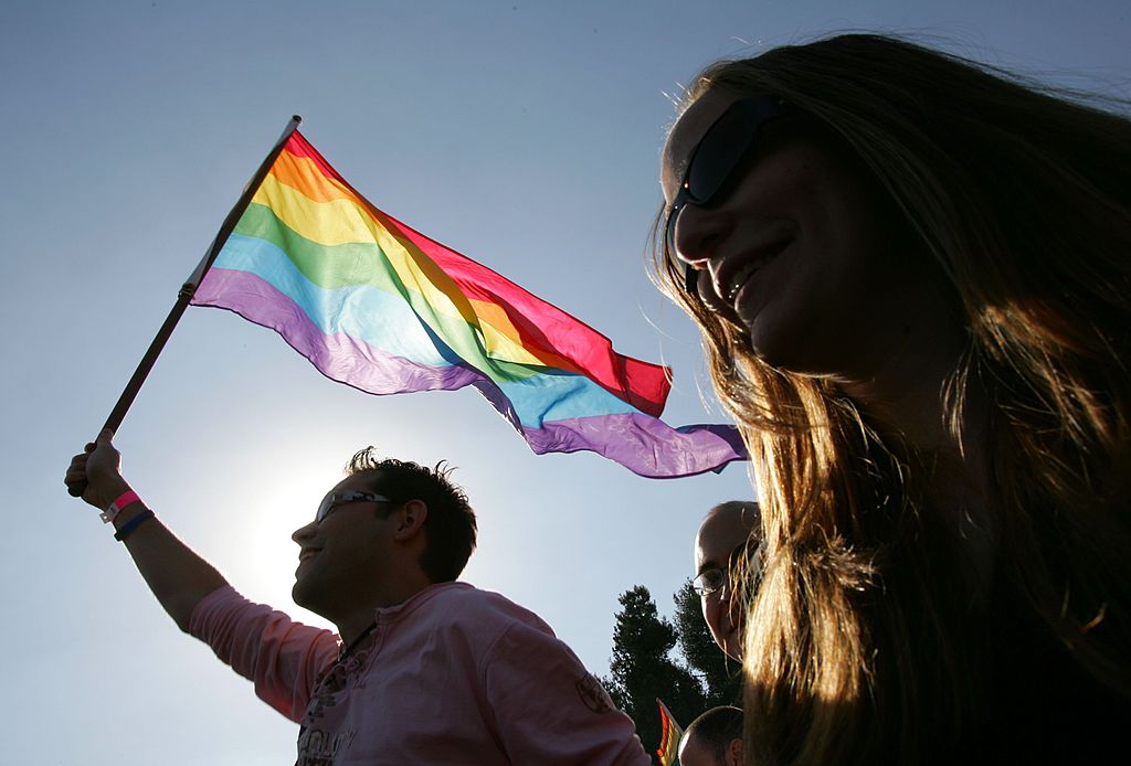 Homem segurando uma bandeira do movimento LGBTQ