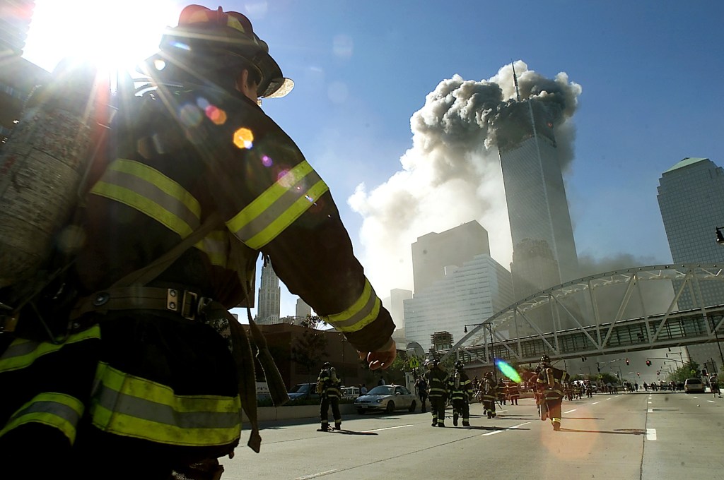 As torres gêmeas do World Trade Center são atingidas por um avião comercial no atentado terrorista de 11 de setembro de 2001 - Bombeiros caminham em direção a uma das torres antes do desabamento.