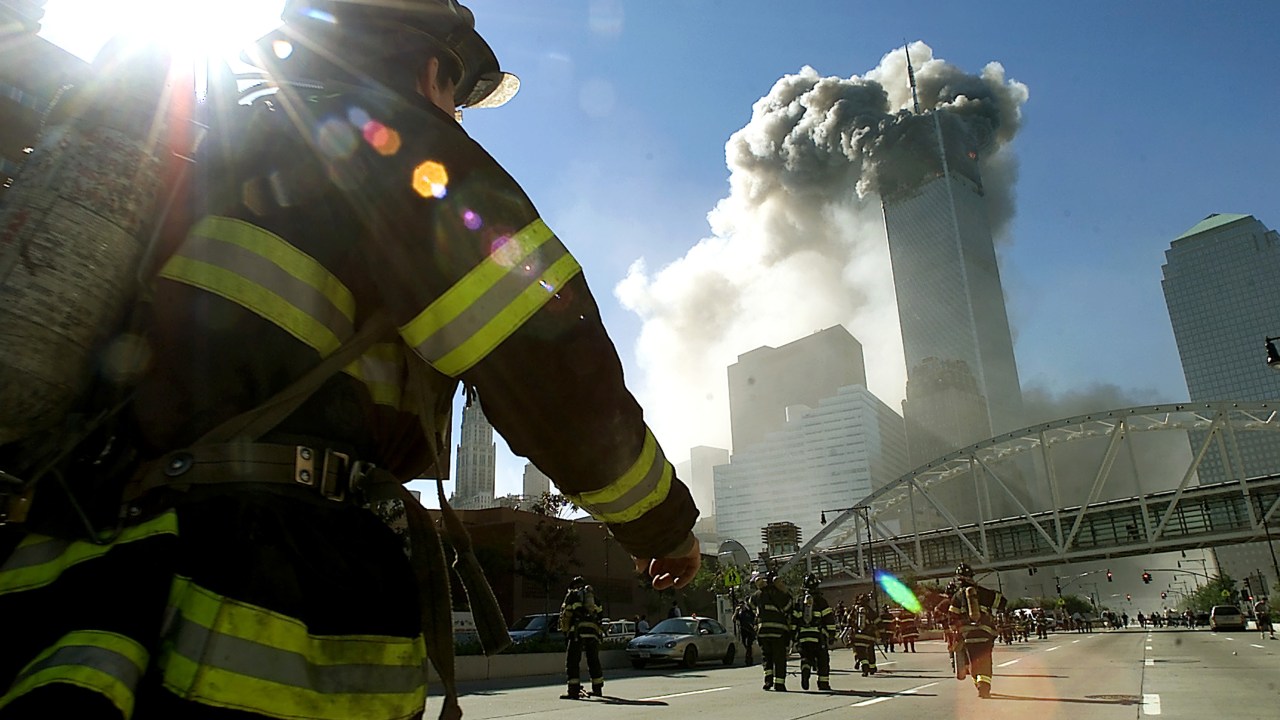 As torres gêmeas do World Trade Center são atingidas por um avião comercial no atentado terrorista de 11 de setembro de 2001 - Bombeiros caminham em direção a uma das torres antes do desabamento.