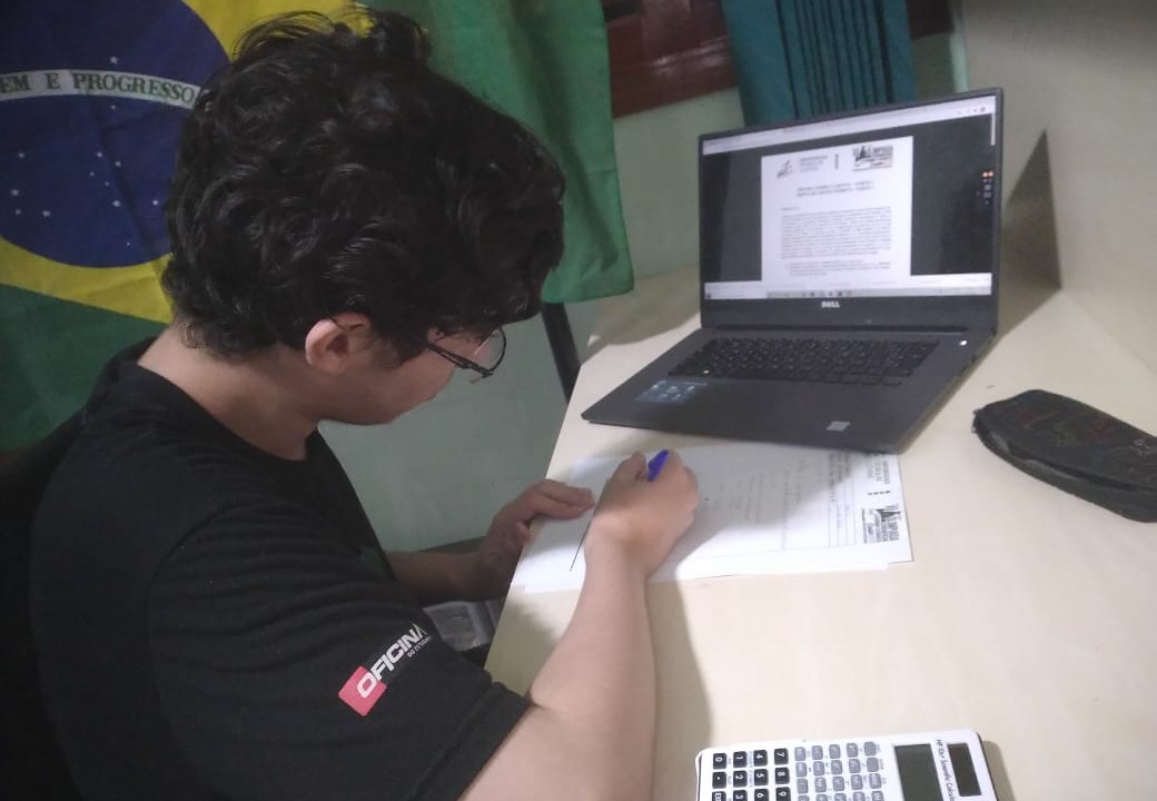 Eduardo em frente à sua mesa, com o computador aberto, estudando para uma das etapas da OLAA.