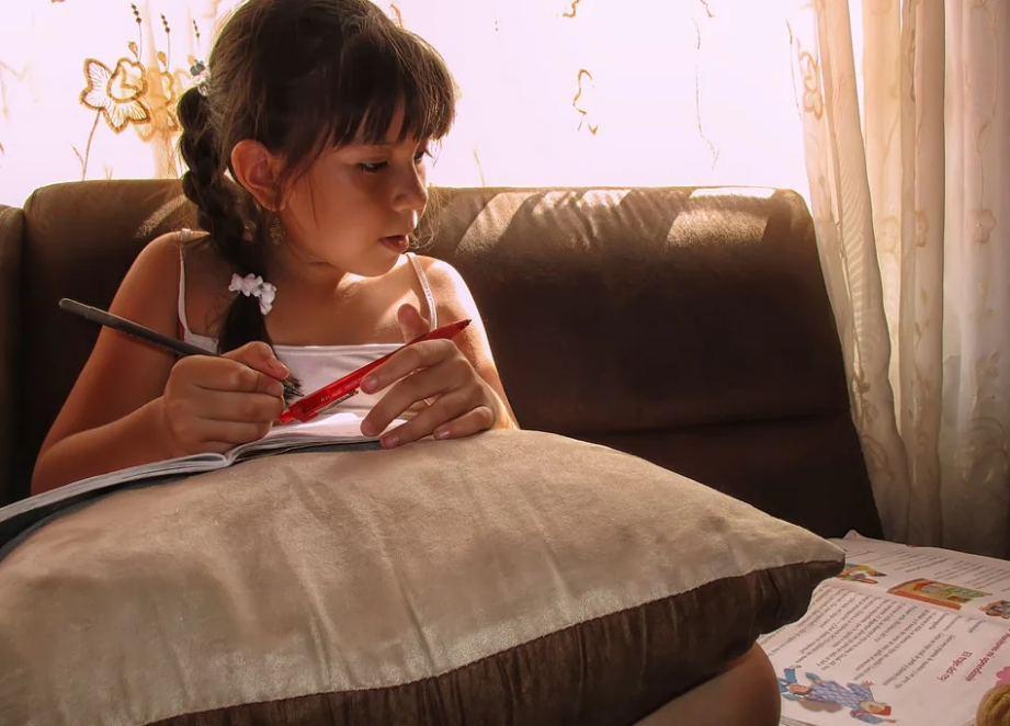 Menina estudando em casa com livro didático