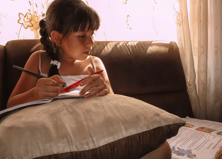 Menina estudando em casa Menina estudando em casa com livro didático
