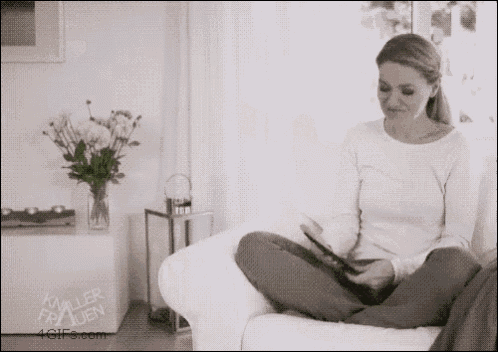Mulher termina de ler livro digital e o coloca na estante, onde guarda vários outros e-readers.