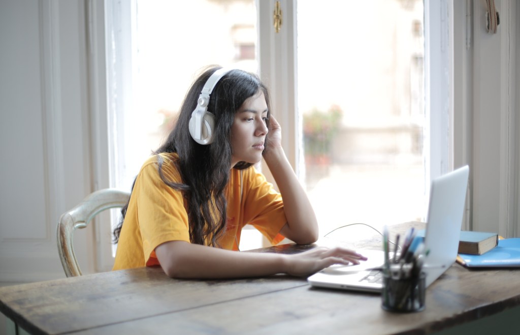 Garota com fone de ouvida na frente do computador