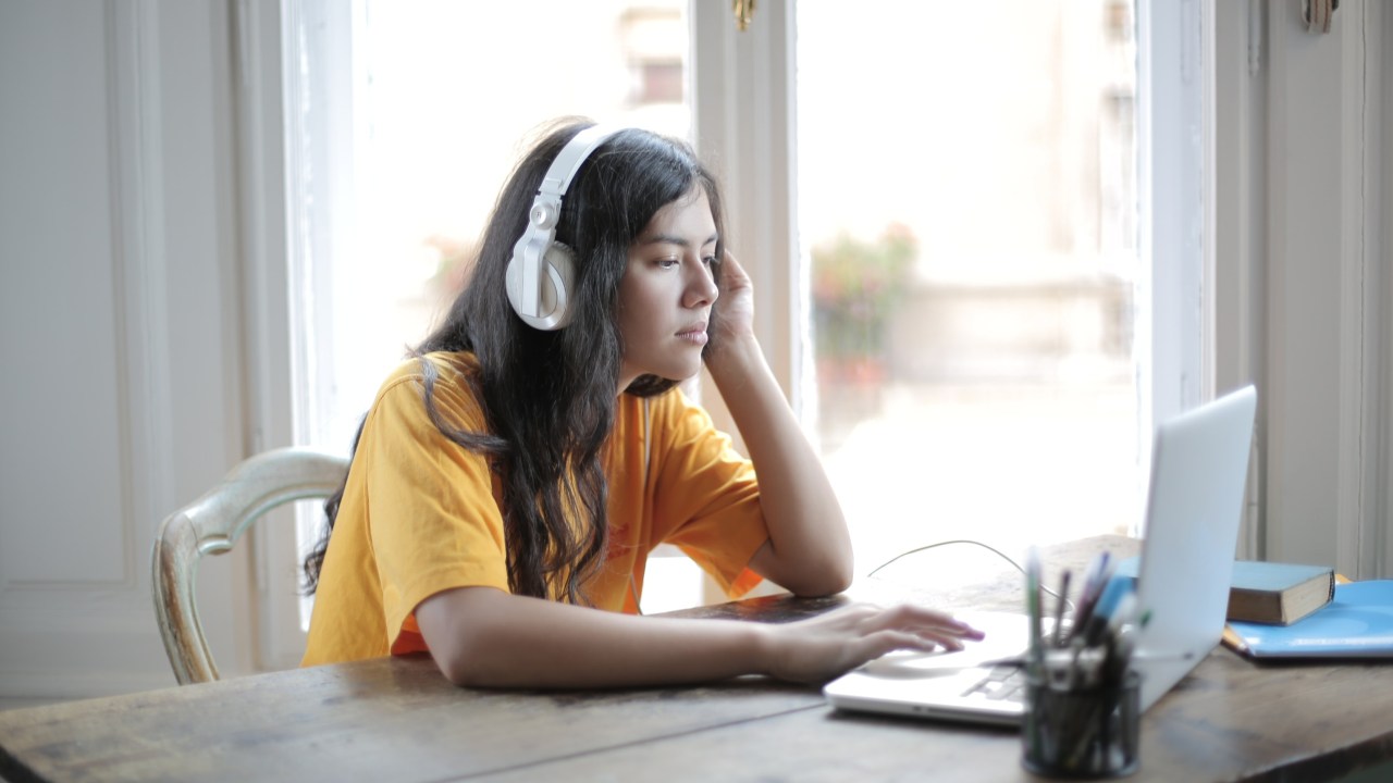 Garota com fone de ouvida na frente do computador