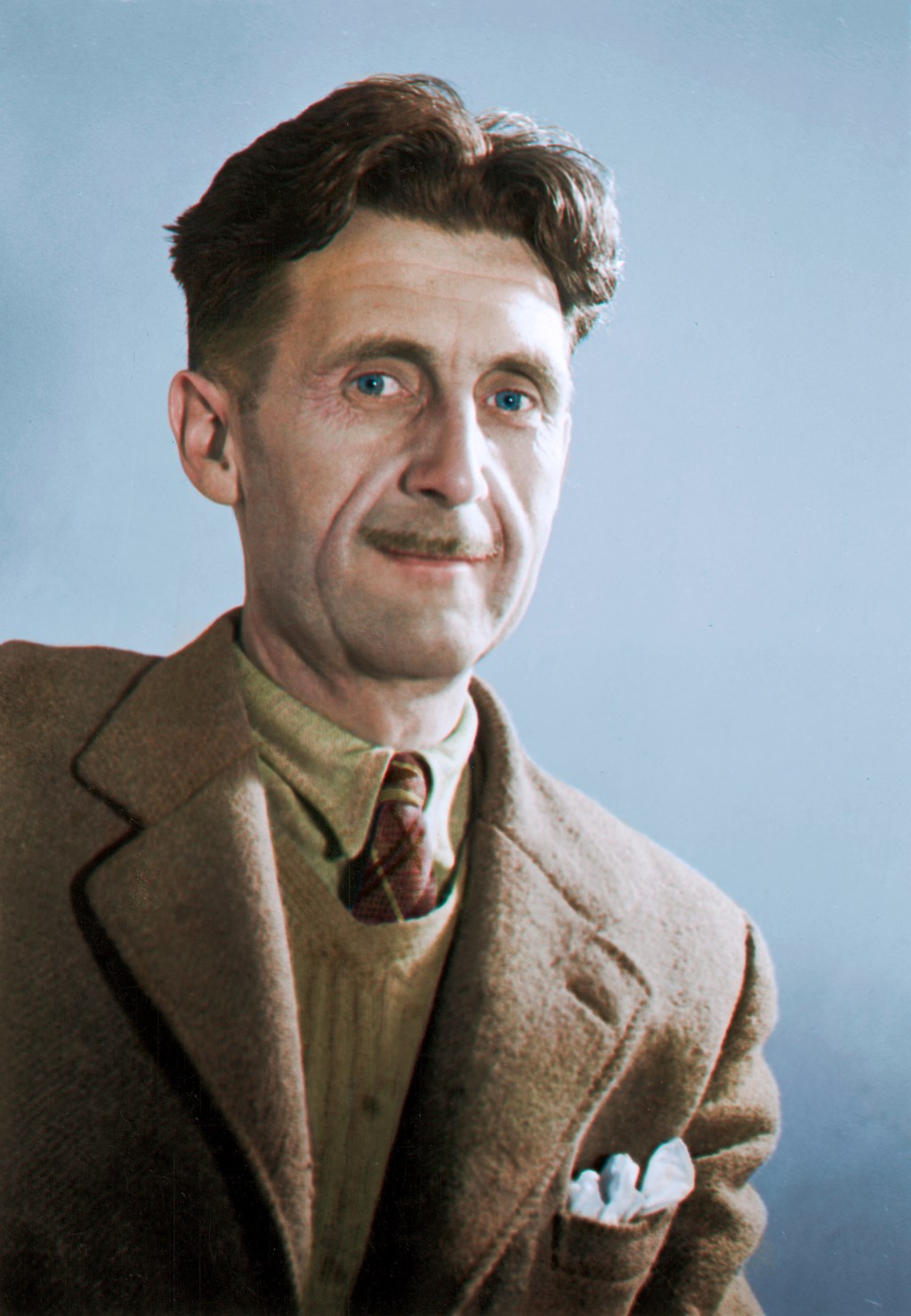 Retrato do autor George Orwell, da altura do peito para cima. Orwell é um homem branco, de cabelos castanhas e olhos azuis. Tem um bigode fino e está usando um blaser, um colete e uma camisa em tons marrons.