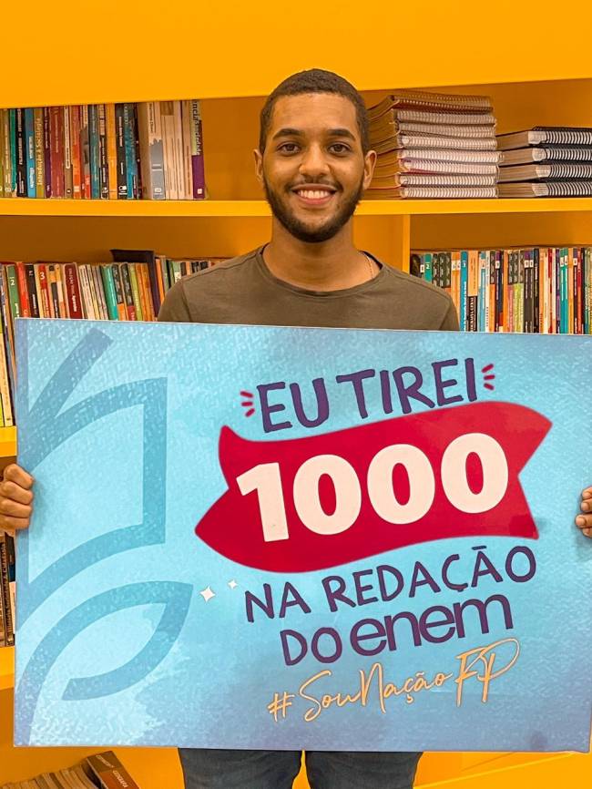 Jovem negro segurando uma placa com os dizeres 