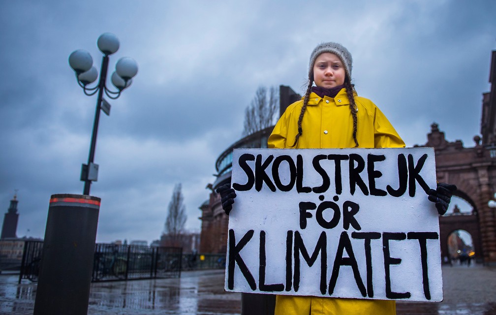 Greta segura um placa em uma praça sueca. Na placa, se lê o protesto inicial de Greta: 