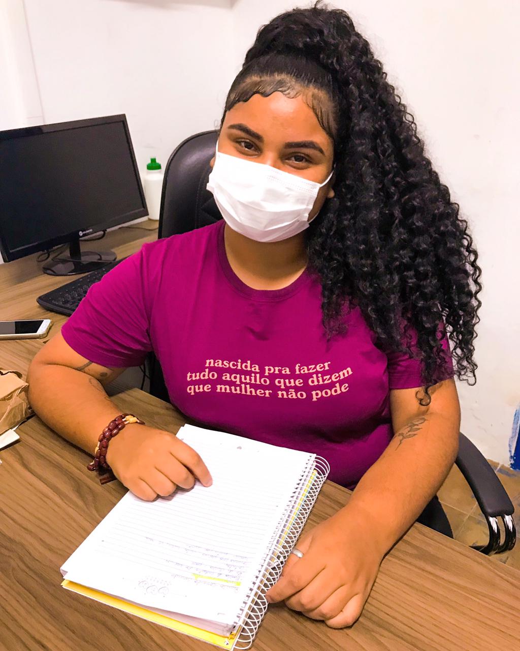 Estudante Jade Beatriz usa máscara em uma mesa com computador e um caderno - Enem 2021