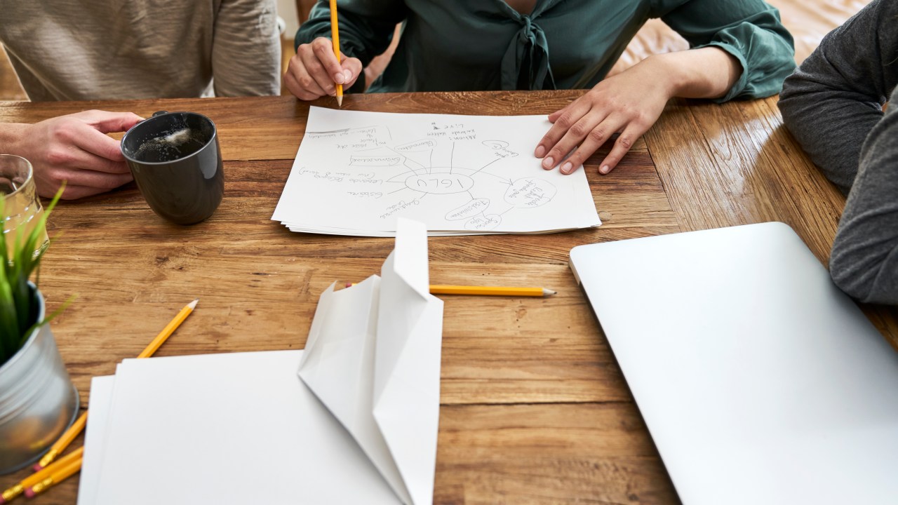 Mesa com papéis e pessoas criando um mapa mental