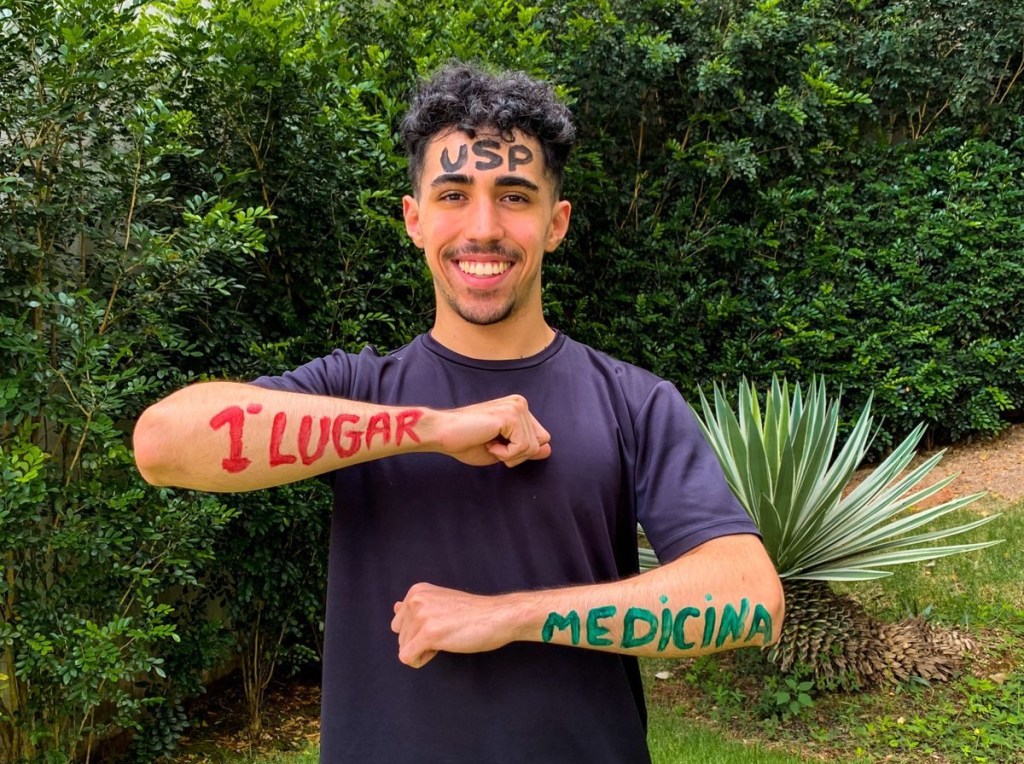 Diego mostrando os braços pintados de tinta com a frase "primeiro lugar" e "Medicina"