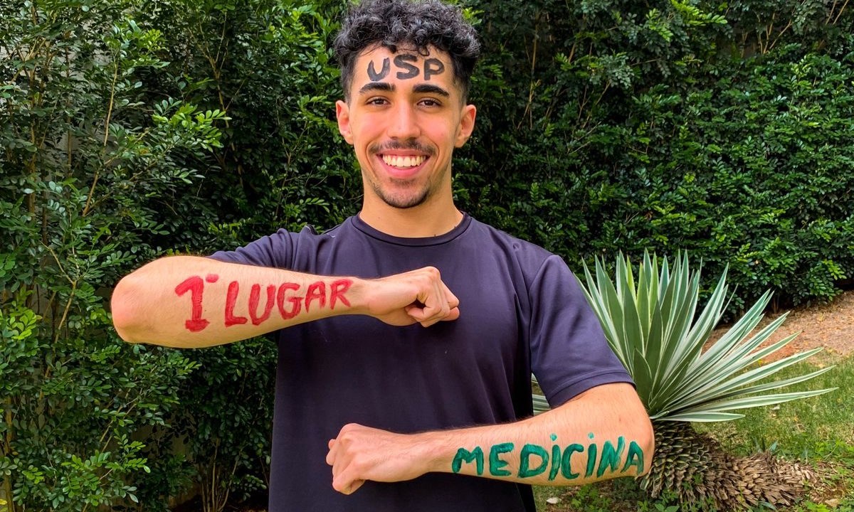 Diego mostrando os braços pintados de tinta com a frase "primeiro lugar" e "Medicina"