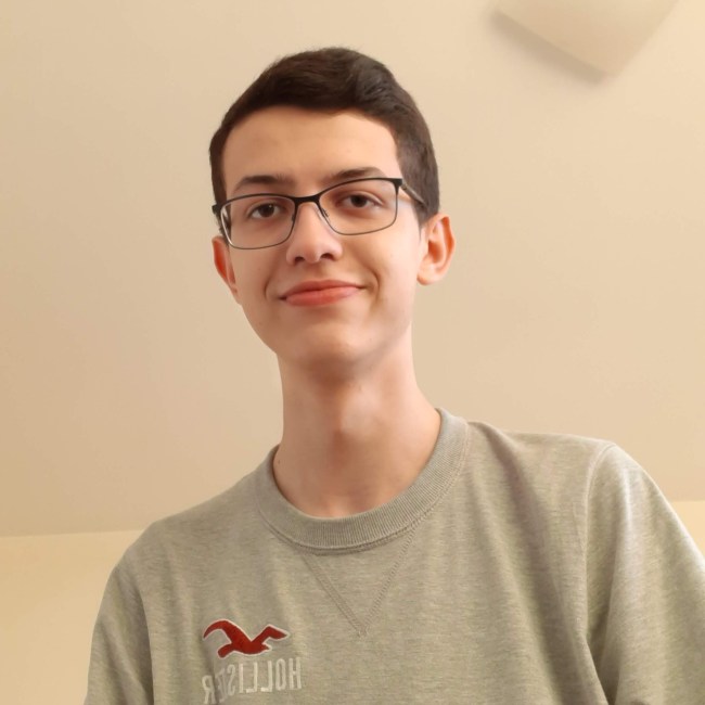 Foto do estudante André de camiseta cinza e usando óculos