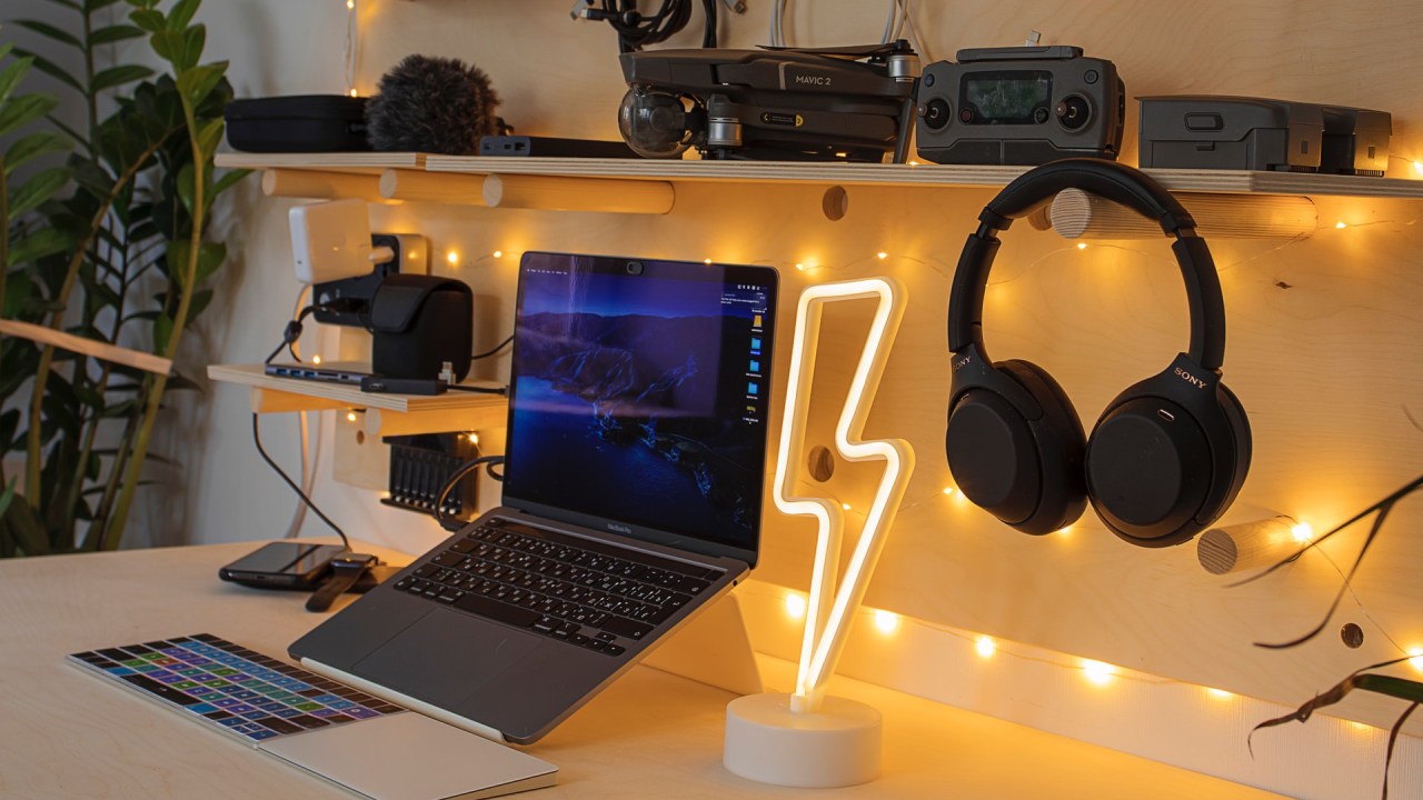 Mesa com computador, fone de ouvido e outros gadgets