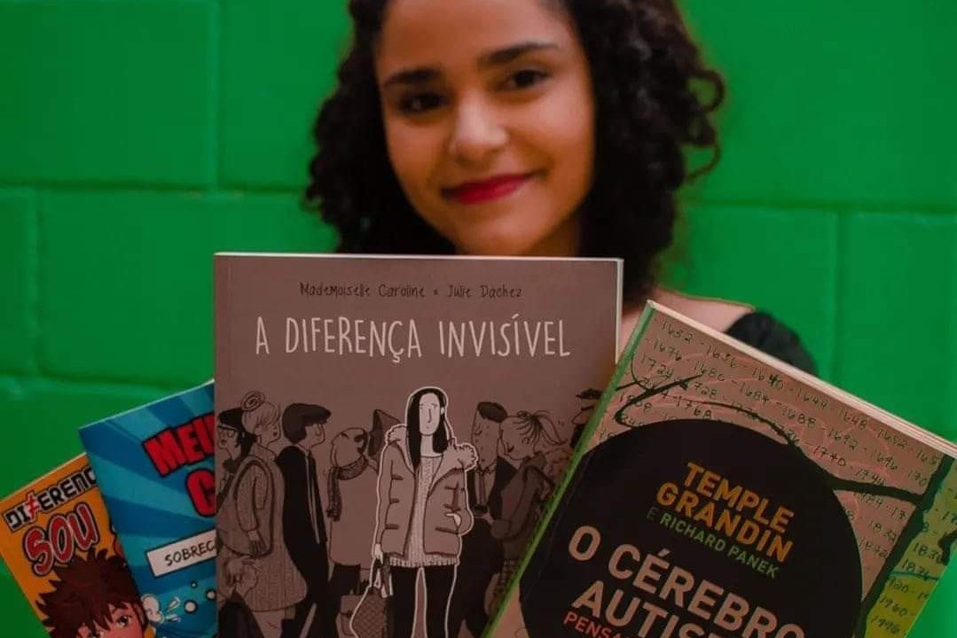 Marcela segurando livros sobre o autismo