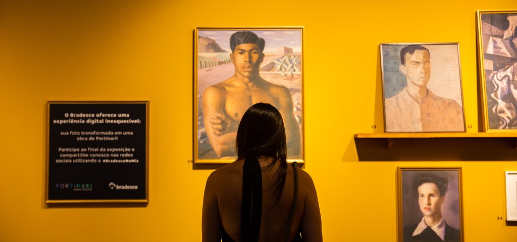 A imagem mostra uma mulher, de costas, observando uma obra de Candidato Portinari
