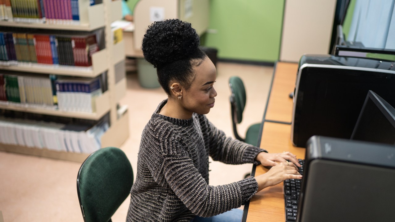 Mulher usando computador em biblioteca