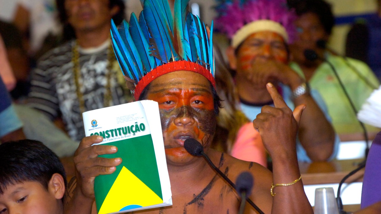 Homem indígena segurando um exemplar da Constituição Federal de 1988