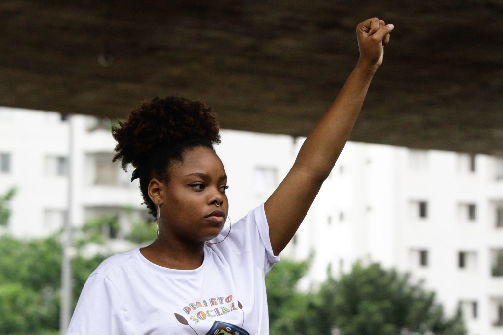 Jovem negra com o punho levantado em protesto 