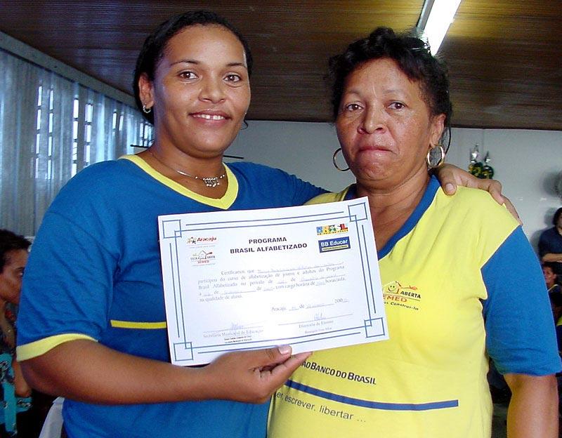 Duas mulheres seguram um diploma do programa Brasil Alfabetizado nas mãos