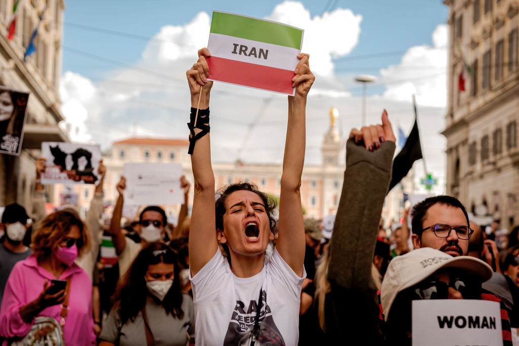 mulher segura cartaz com a bandeira do irã durante protesto contra ditadura no país