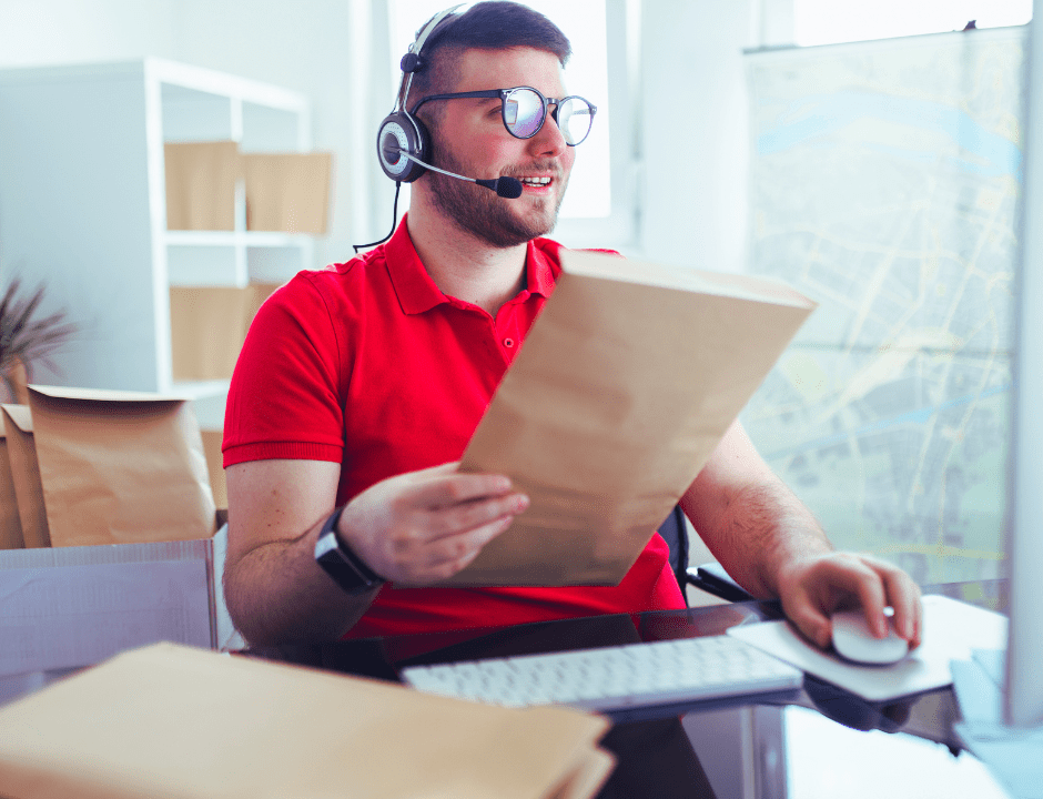 Homem segurando e selecionando envelopes, na frente de um computador