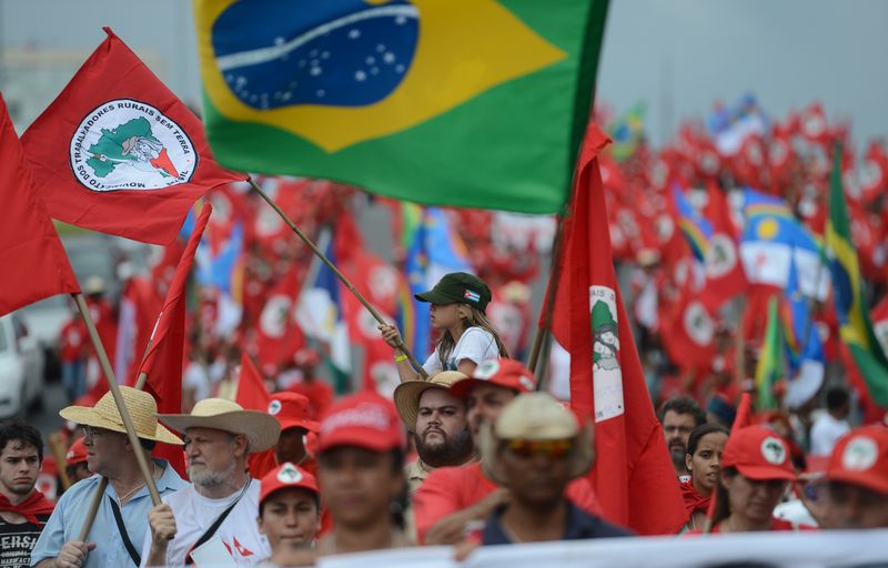 manifestantes do MST em Brasília carregam bandeiras do movimento e do Brasil