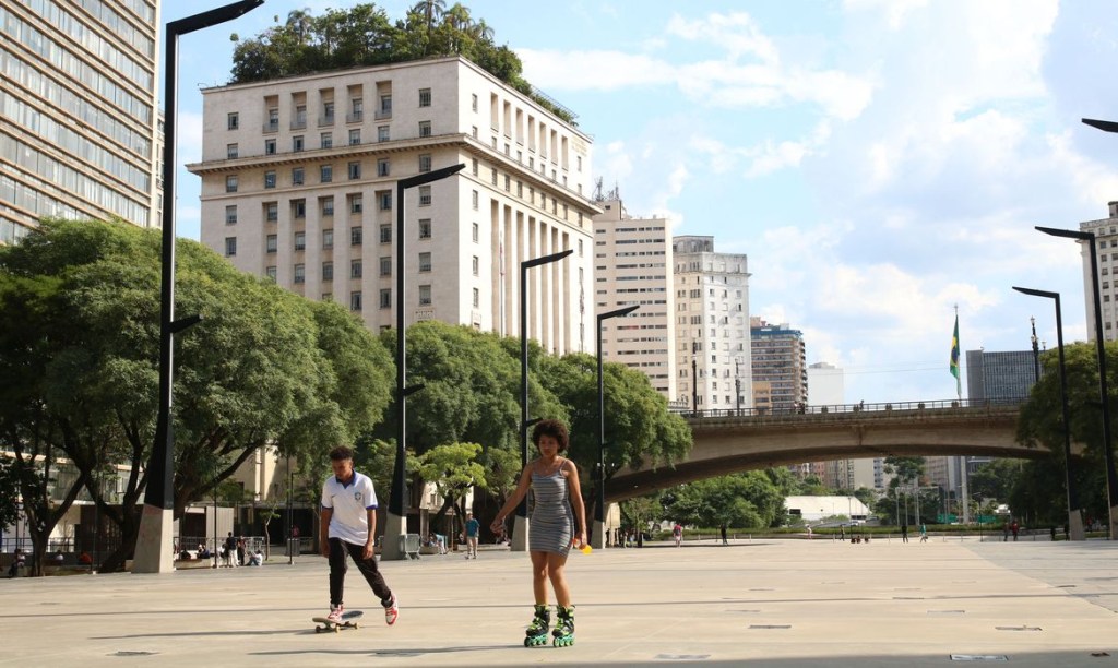 Jovens praticando esportes, andando de patins, em via pública da cidade