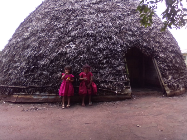 Duas crianças em frente a uma oca indígena