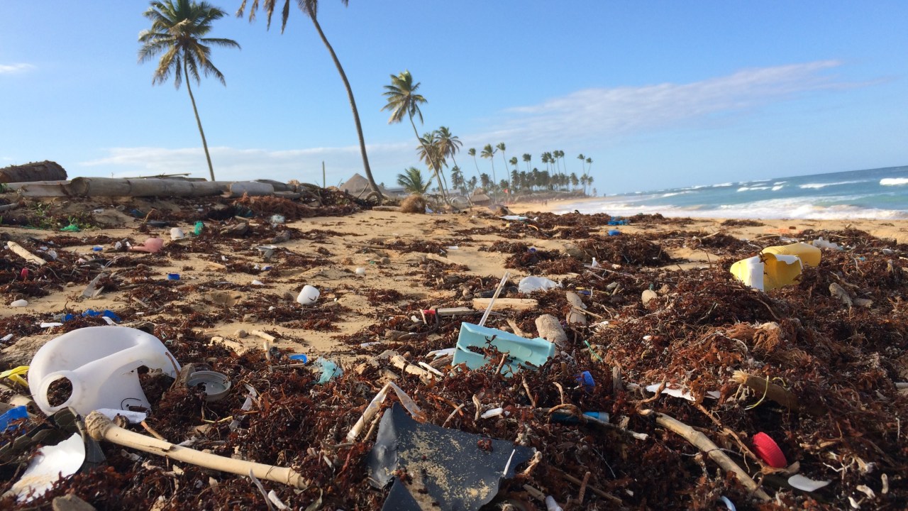 praia poluída com lixos não degradáveis como plásticos