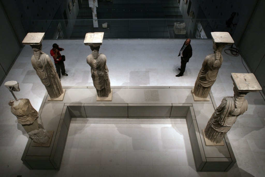 Exposição das 5 cariátides no Museu da Acrópole. Há um espaço vago entre elas.