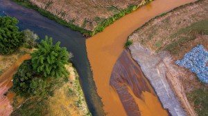 O rio Gualaxo do Norte despeja lama tóxica vinda da barragem da Samarco, em Mariana (80 km rio acima), no rio Carmo (à esq.), em foto de 2016; cerca de 25 km depois, a lama atinge o rio Doce, um dos mais importantes do Sudeste do Brasil