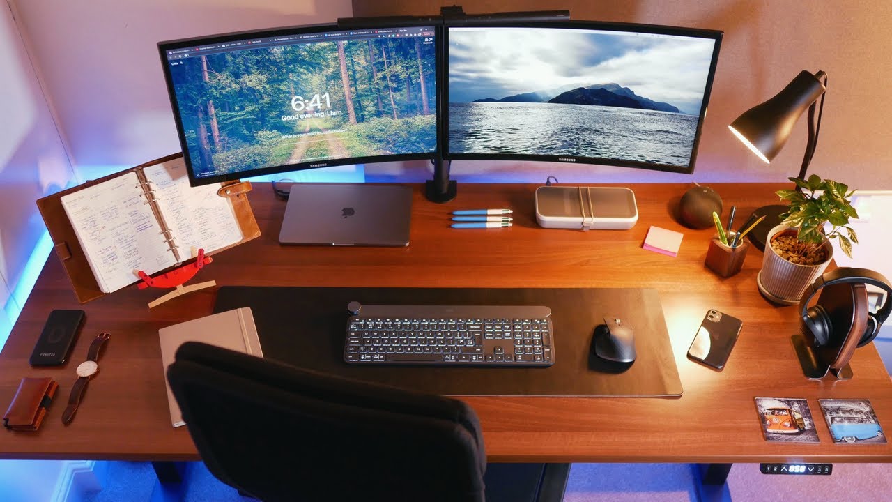 Mesa com dois monitores, teclado e mouse sem fio e outros apetrechos
