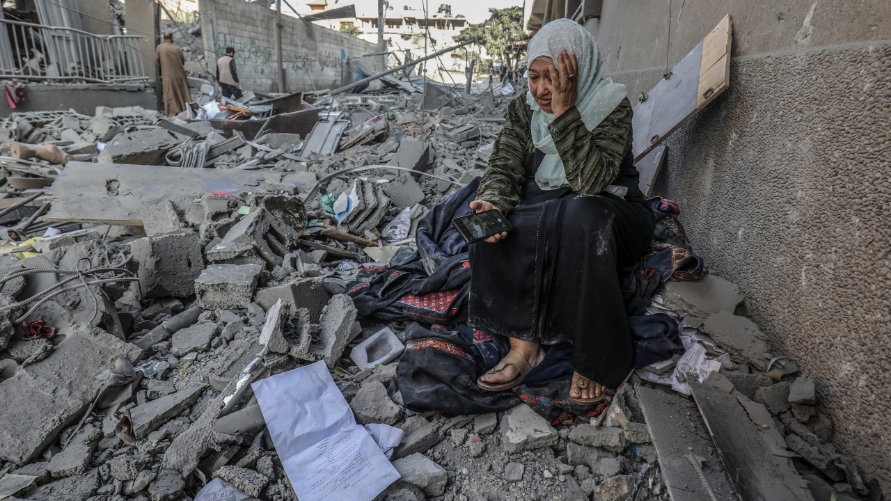 Mulher palestina sentada sobre as ruínas de sua antiga casa na Faixa de Gaza.