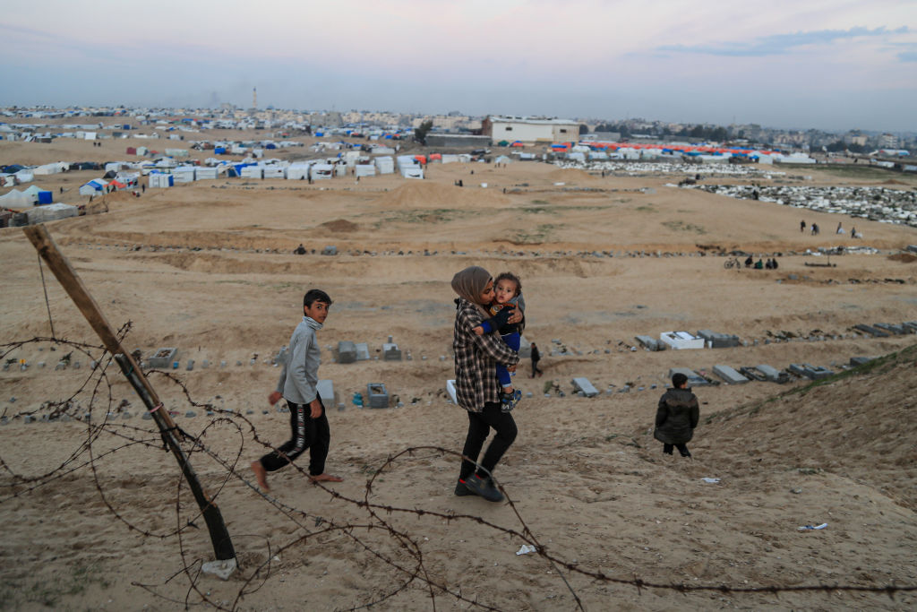 mulher e criança palestinos se deslocam em território árido