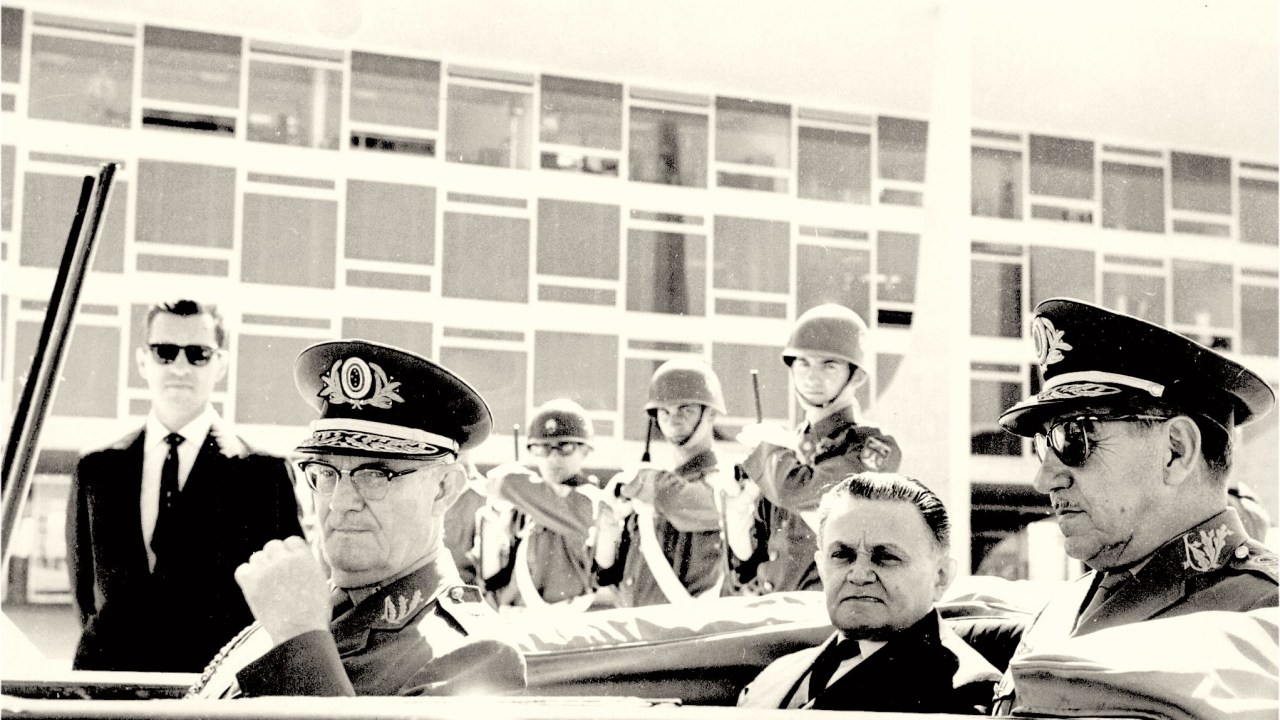 Carro oficial passa em frente ao Palácio do Planalto com o presidente Castelo Branco (mandato de 1964 a 1967) e os generais (e futuros presidentes) Ernesto Geisel (à esq.) e Costa e Silva